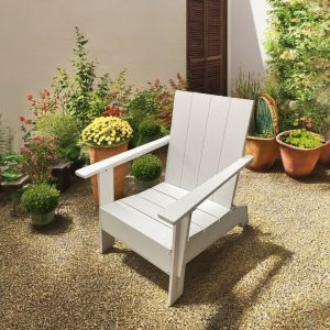 Ghế Adirondack ngoài trời màu trắng đặt trong sân vườn nhiều cây cảnh