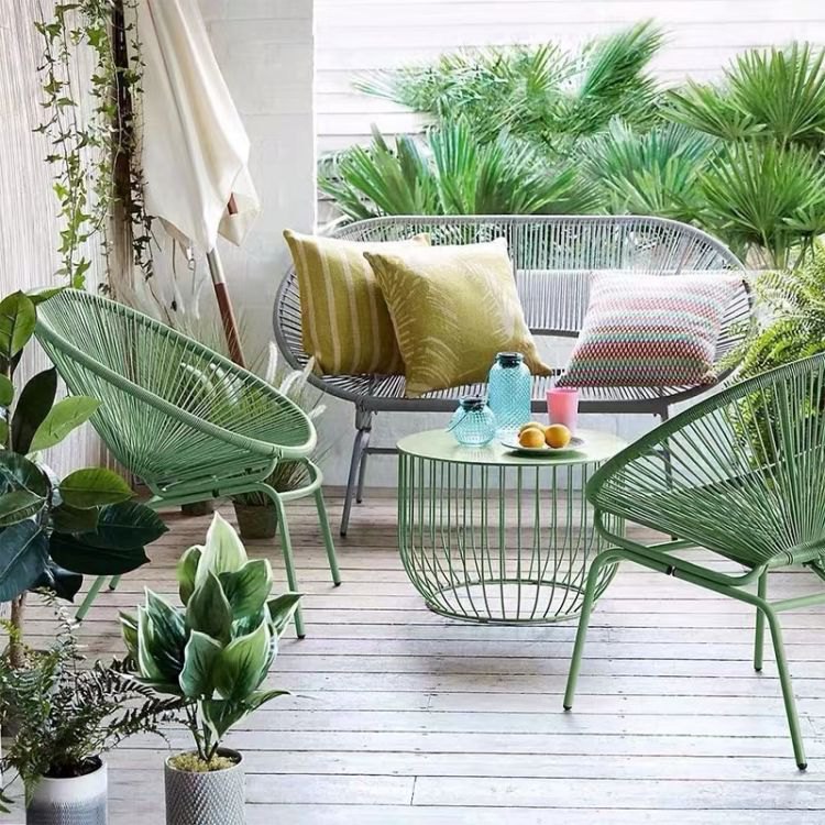 Bộ sofa sân vườn khung nhôm dây nhựa giả mây màu xanh lá, gồm sofa đôi, 2 ghế đơn và bàn trà, bối cảnh ngoài trời xanh mát