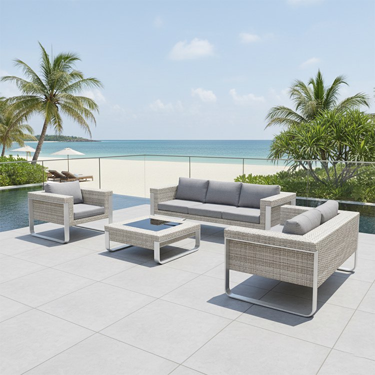 Bộ sofa sân vườn nhựa giả mây 4 món màu xám nhạt, gồm sofa 3 chỗ, 2 ghế đơn và bàn kính, đặt ngoài trời cạnh biển