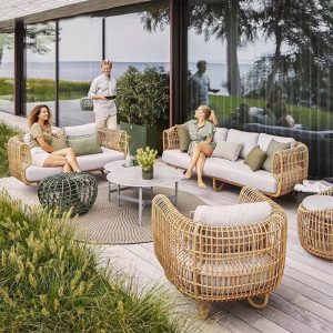 Bộ sofa sân vườn giả mây hiện đại gồm sofa đôi, 2 ghế đơn, bàn trà kính, nệm ghi, bối cảnh ngoài trời sang trọng