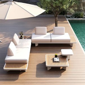 Bộ sofa sân vườn hiện đại 4 món đặt cạnh hồ bơi, khung nhôm trắng, nệm dày màu kem, bàn trà mặt gỗ nhựa.