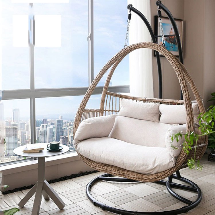 Xích đu đôi giả mây khung sắt nệm màu kem đặt trong phòng khách view thành phố
