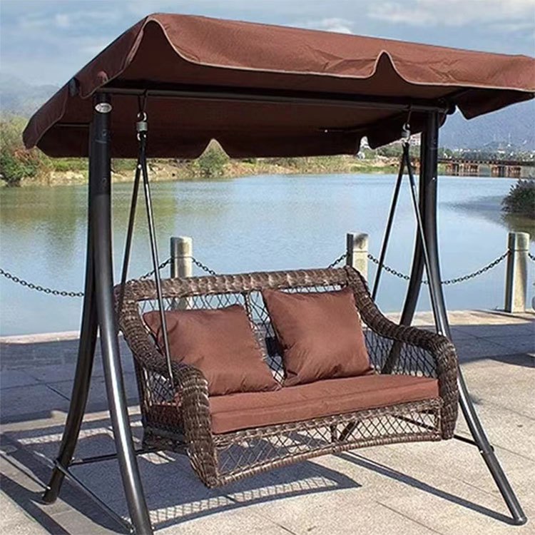 Xích đu sân vườn 2-3 chỗ khung sắt, mây nhựa nâu, nệm nâu, mái che nâu, đặt cạnh hồ nước