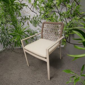 Ghế sân vườn khung nhôm đan dây rope, nệm be, đặt giữa không gian cây xanh ngoài trời