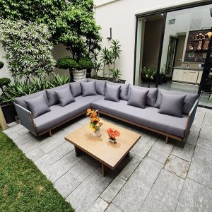 Sofa ngoài trời góc L lớn, nệm dày màu ghi, bàn trà gỗ vuông, phù hợp sân vườn xanh mát