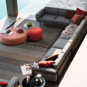 Cận cảnh bộ sofa ngoài trời chữ L, nệm dày, bàn trà tròn bọc nệm màu cam, không gian mở