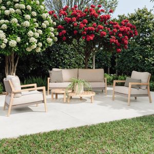 Bộ sofa ngoài trời gỗ teak với nệm be sáng trong vườn hoa rực rỡ
