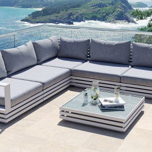 Bộ sofa ngoài trời chữ L màu trắng, nệm xám, bàn trà kính, view biển sang trọng