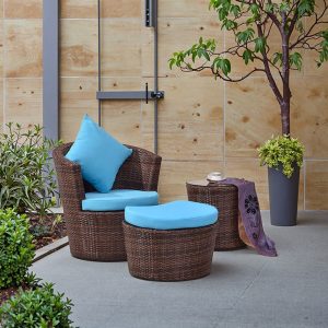 Bộ bàn ghế sân vườn giả mây, nệm xanh dương, đặt ngoài trời cạnh cây xanh