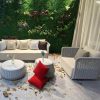 Bộ sofa sân vườn giả mây màu trắng xám, nệm dày, nhiều gối tựa, bối cảnh vườn đứng xanh mát