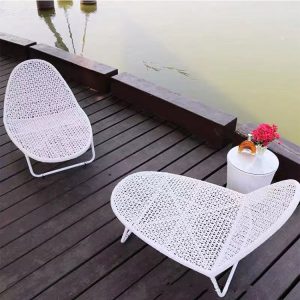 Bộ ghế tắm nắng nhựa giả mây trắng đặt cạnh hồ nước, đi kèm bàn phụ nhỏ
