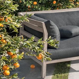 Cận cảnh sofa góc L khung gỗ teak, nệm xám đậm, đặt giữa vườn cây cam