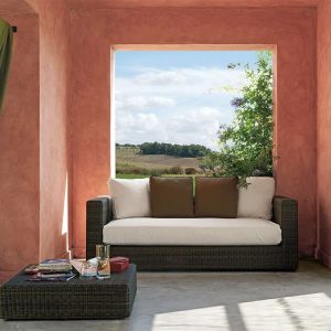 Sofa ngoài trời giả mây màu nâu xám, nệm trắng, gối tựa nâu, đặt trong không gian mở