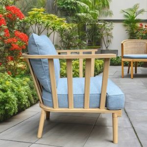 Ghế đơn sofa ngoài trời, khung nan thẳng, nệm xanh dương nhạt, đặt trong vườn cây xanh