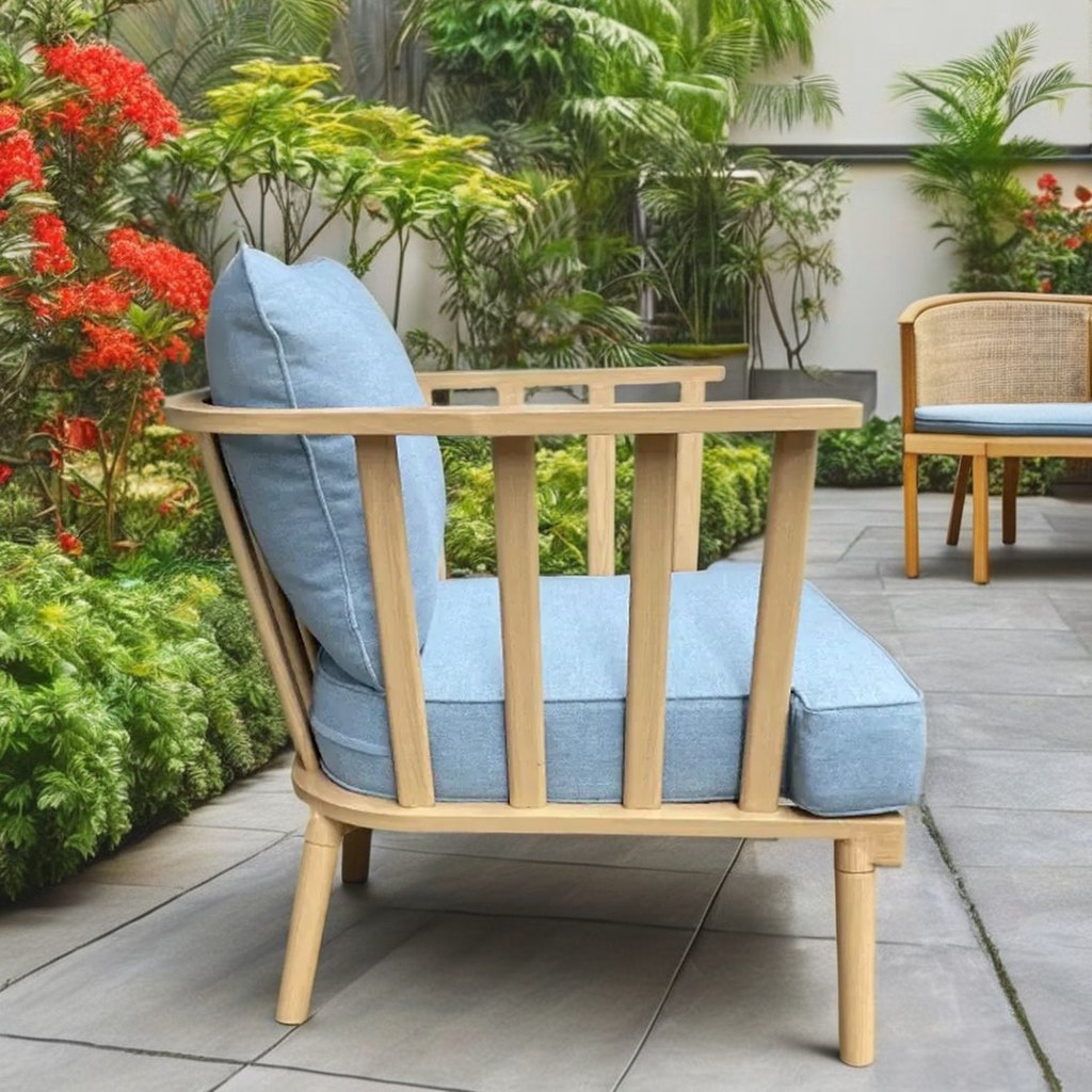 Ghế đơn sofa ngoài trời, khung nan thẳng, nệm xanh dương nhạt, đặt trong vườn cây xanh