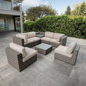 Bộ sofa sân vườn giả mây màu xám, nệm kem, kê ngoài trời cạnh vườn cây