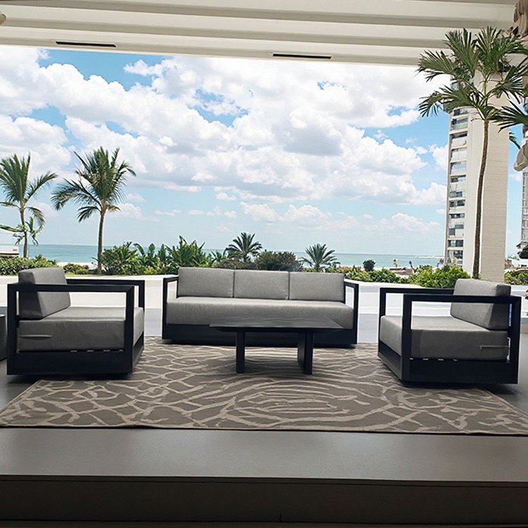 Bộ sofa sân vườn hiện đại, nệm xám, đặt trên thảm ngoài trời cạnh biển