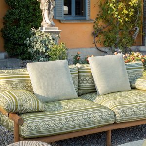 Cận cảnh nệm sofa dài ngoài trời, vỏ vải dệt họa tiết xanh lá, gối tựa lớn màu kem
