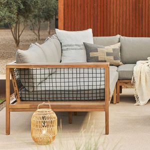 Cận cảnh góc sofa chữ L ngoài trời, khung gỗ teak, dây đan, nệm và gối tựa màu ghi