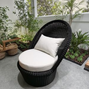 Ghế đơn nhựa giả mây ngoài trời, nệm trắng và gối tựa, đặt cạnh cây xanh thư giãn