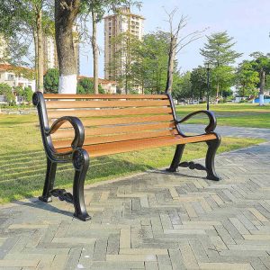 Ghế băng công viên khung gang, thanh gỗ màu nâu, đặt cạnh lối đi lát gạch, phù hợp sân vườn biệt thự