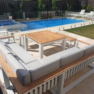 Bộ sofa sân vườn góc L thực tế ngoài trời cạnh hồ bơi, khung trắng, nệm xám, bàn mặt gỗ