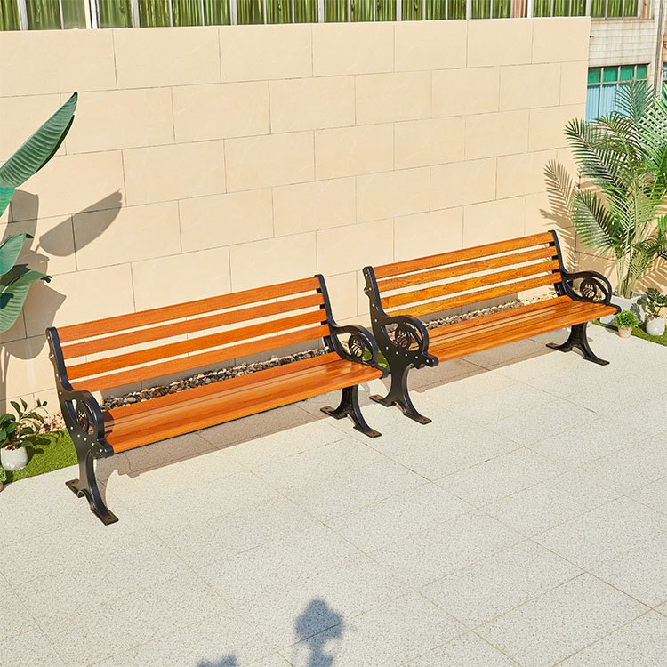 Hai ghế băng dài ngoài trời nhựa giả gỗ màu nâu vàng, khung sắt đen, đặt ở sân vườn rộng.