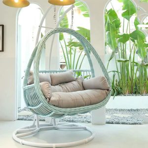Xích đu đôi giả mây màu trắng xanh, nệm be sáng, không gian sân vườn nhiệt đới