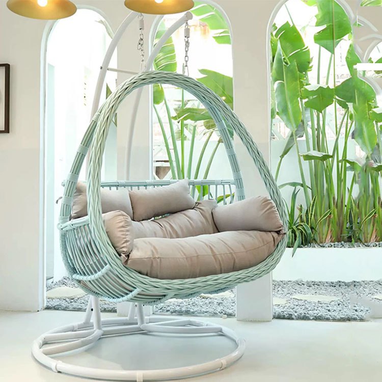 Xích đu đôi giả mây màu trắng xanh, nệm be sáng, không gian sân vườn nhiệt đới